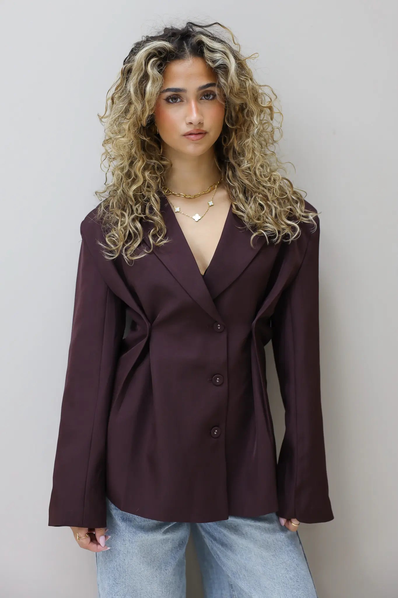 model draagt bordeaux blazer frontaal voor lichte muur