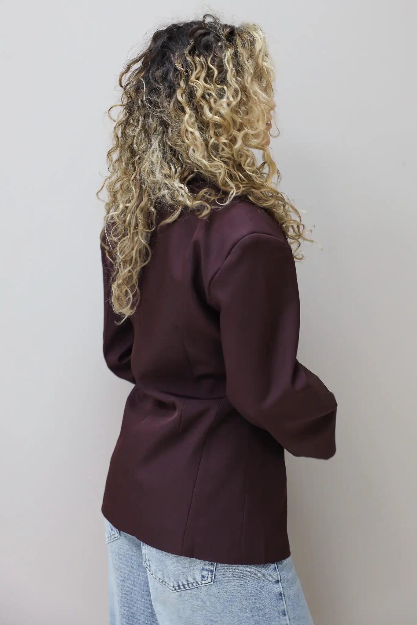model staat met rug naar camera in bordeaux blazer