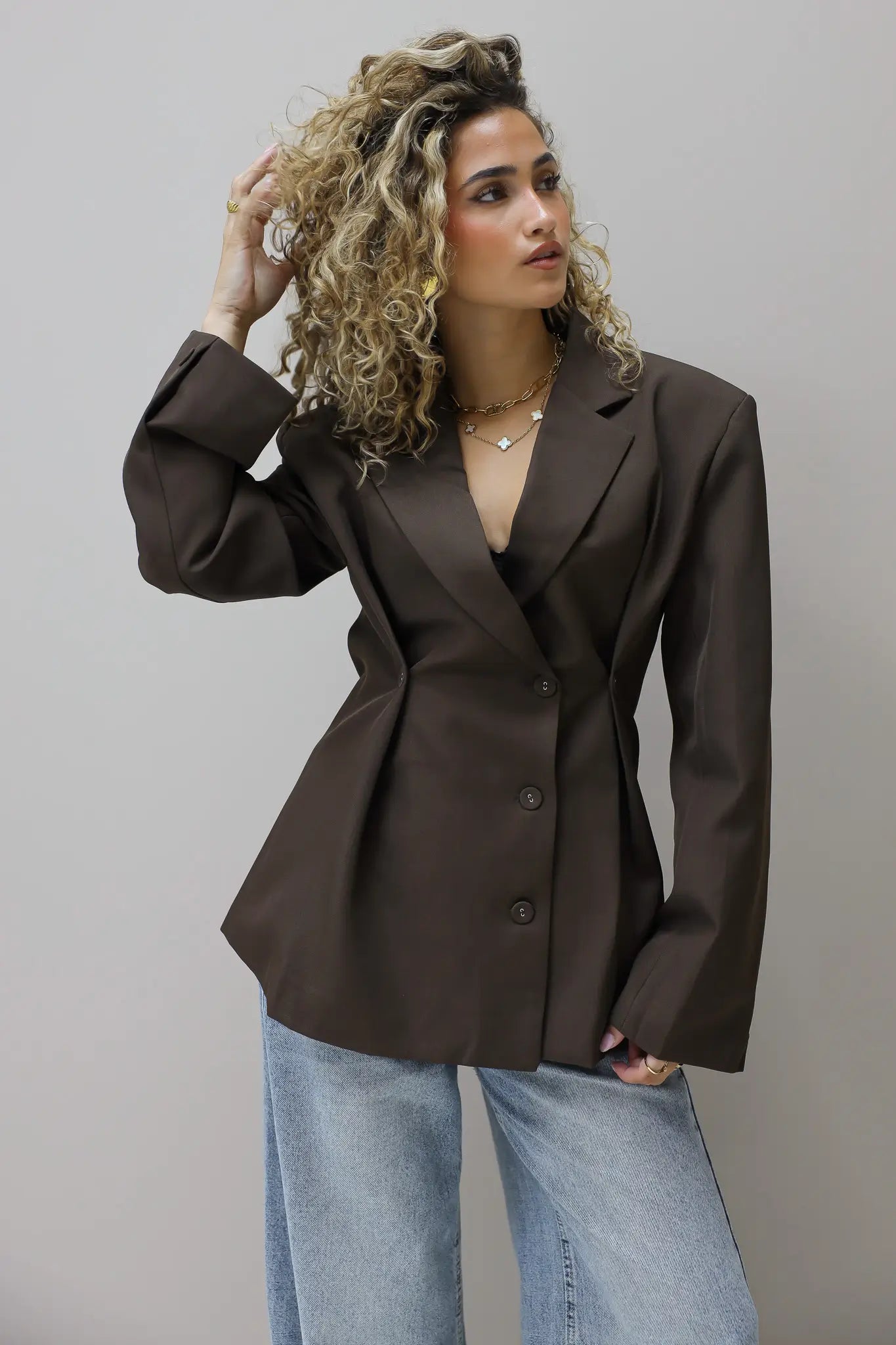 model draagt bruine blazer met jeans gezien van opzij