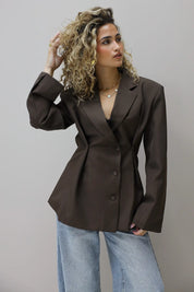 model draagt bruine blazer met jeans gezien van opzij