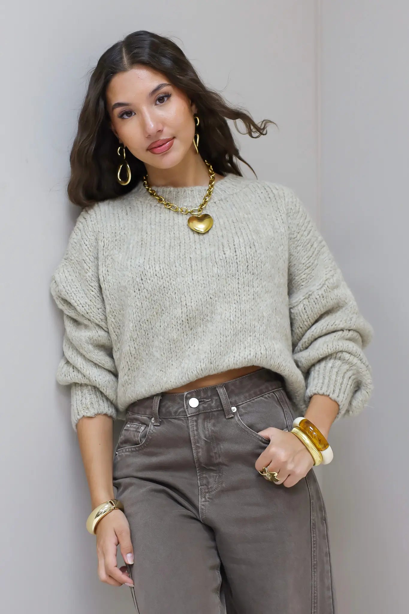 Model staat recht in beige trui met bruine broek