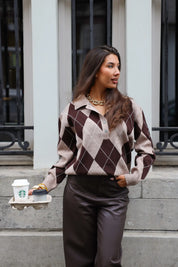 Model met argyle trui bruin beige tegen muur, casual pose