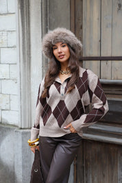 Model draagt argyle trui met taupe fluffy muts