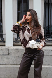 Model met argyle trui bruin beige poseert rechtop met koffie