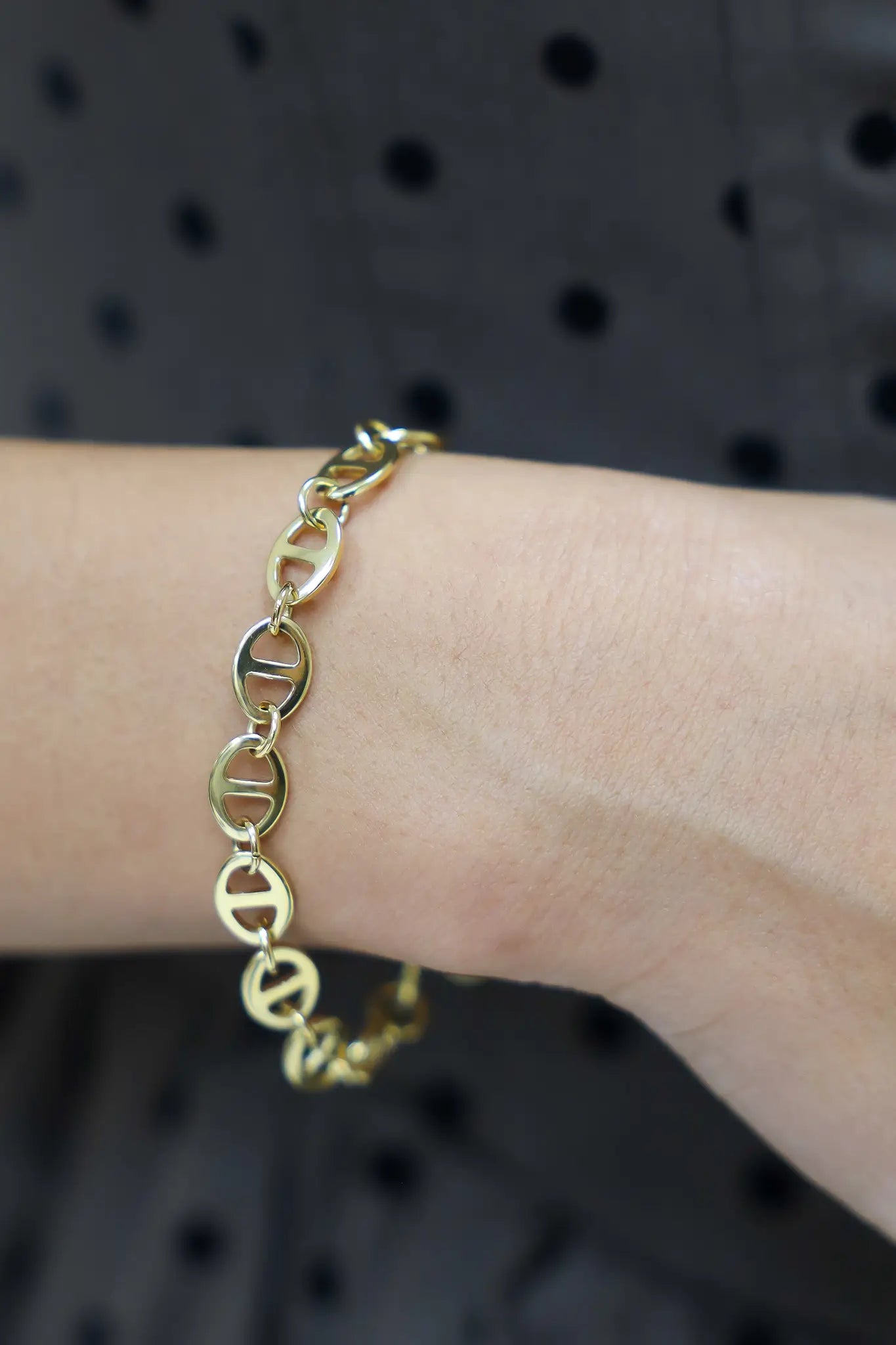 armband linked goud met logo hanger close up