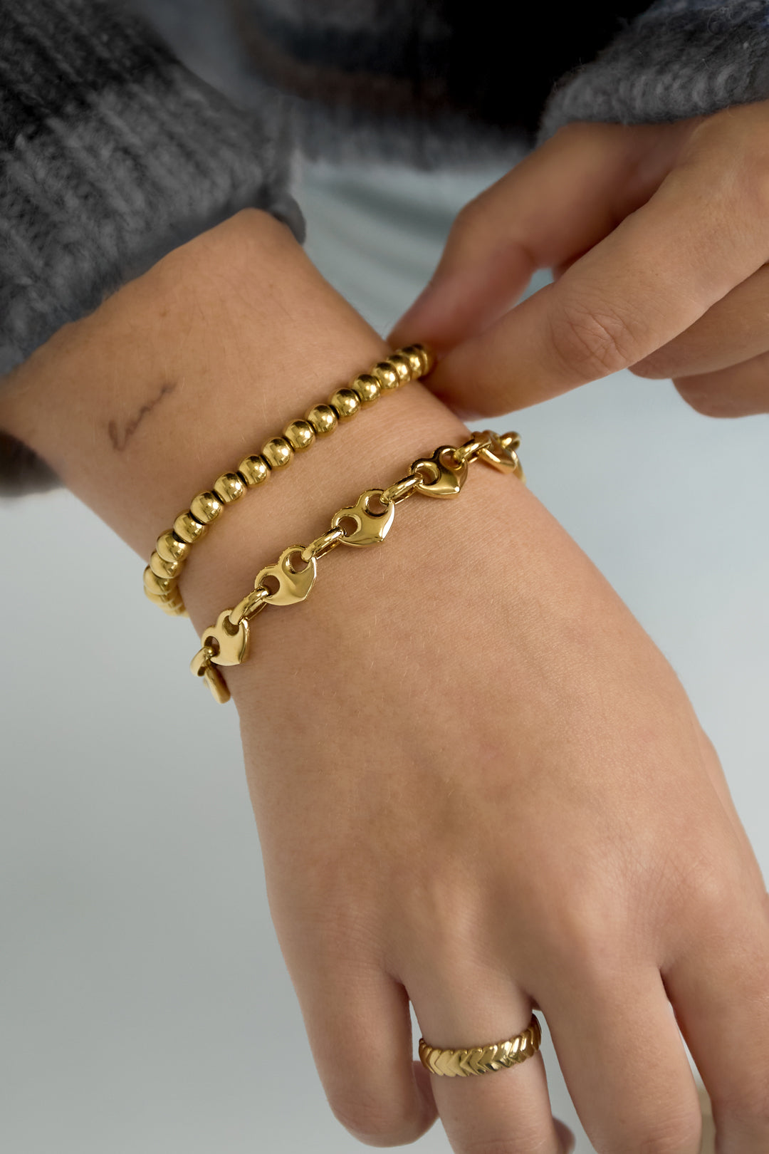 Pols met gouden hartjes schakelarmband om de hand