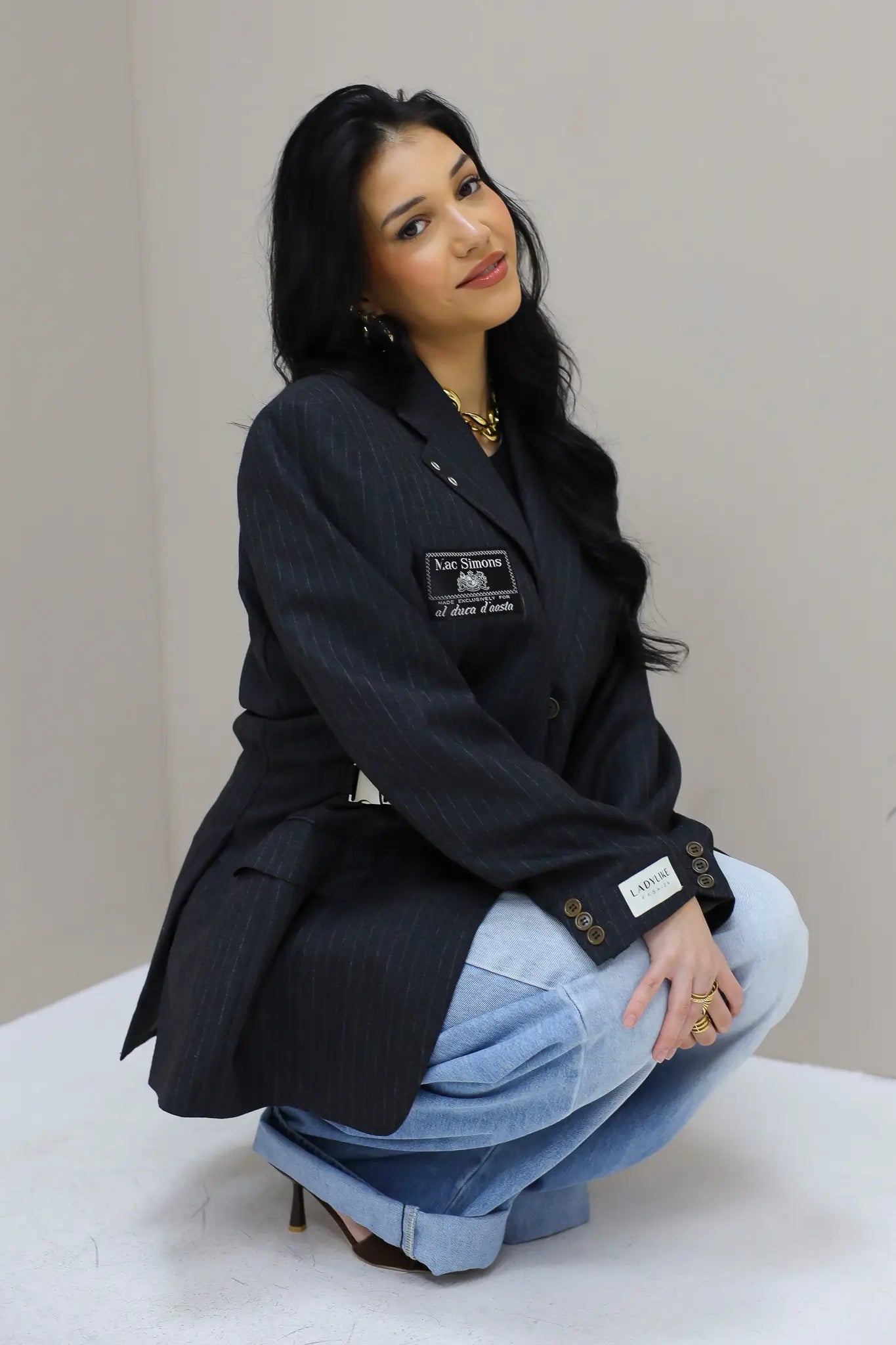 model poseert in hoek met gestreepte blazer