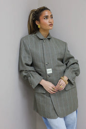 Close up van voorkant met knopen en borstzak van grijze blazer