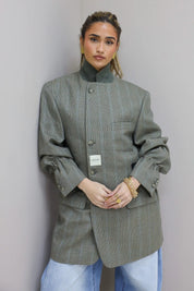 Rechtstaande look met grijze blazer en lichte jeans