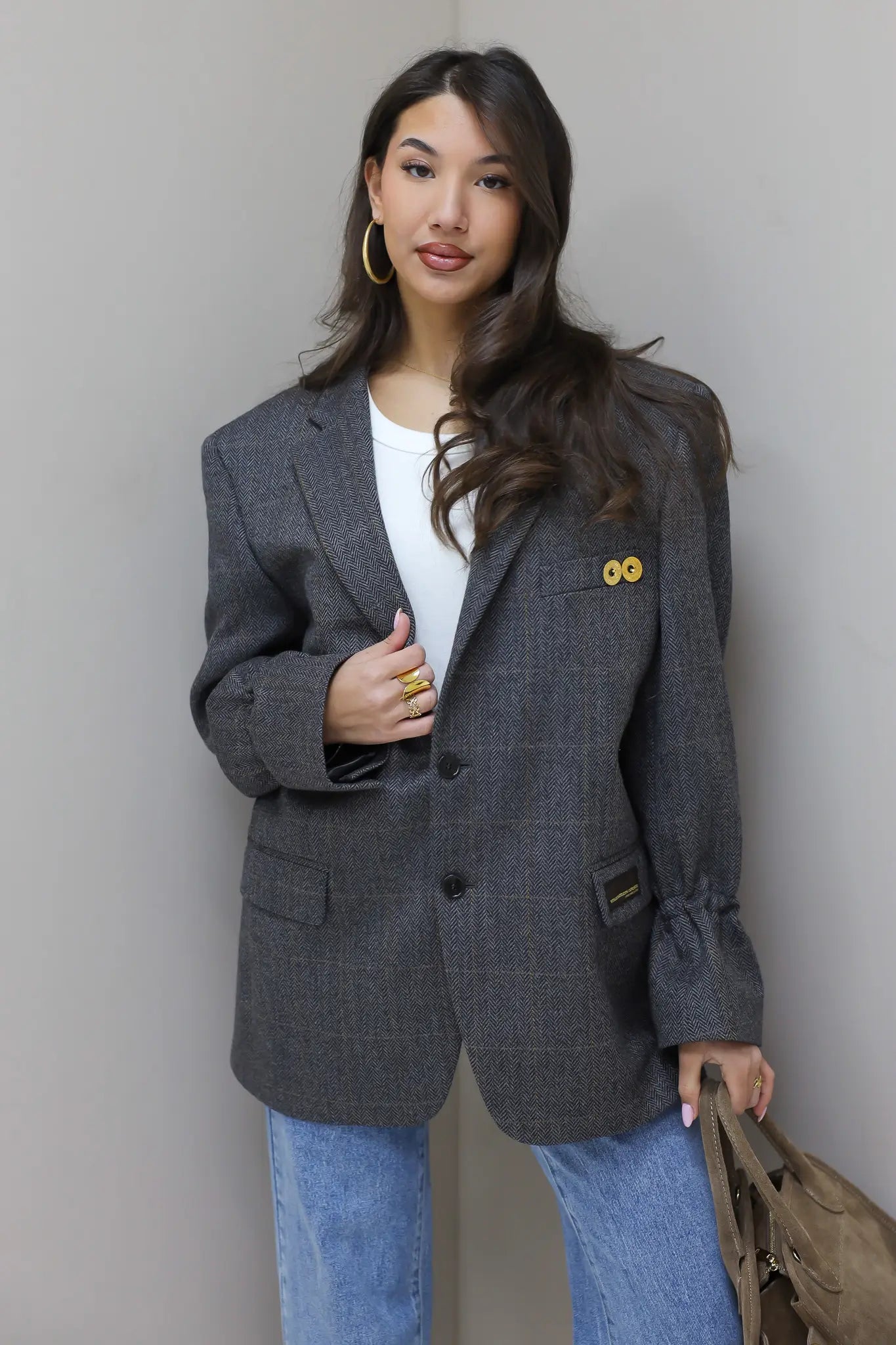 Oversized grijze blazer tegen neutrale achtergrond