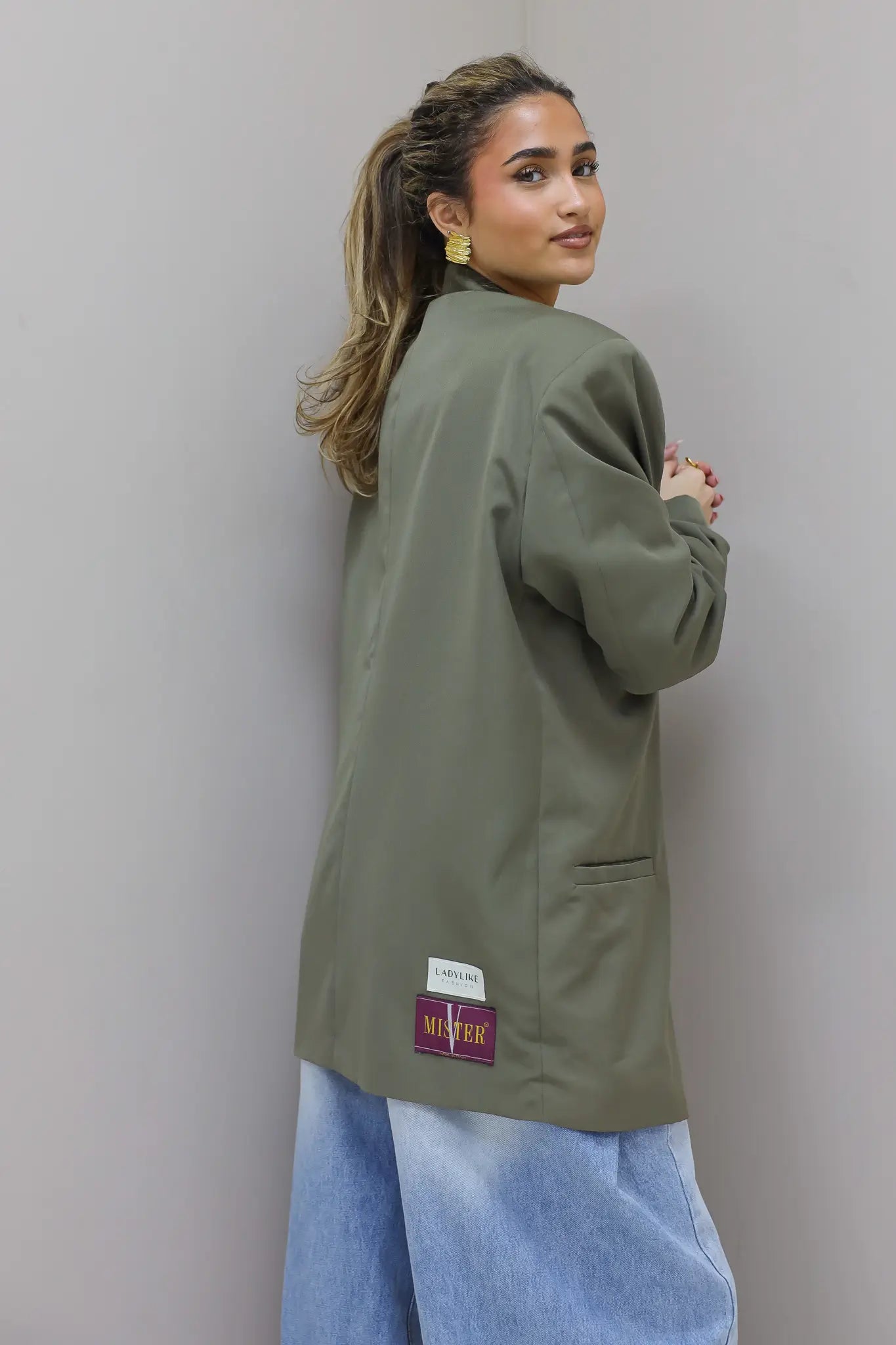 Achteraanzicht van oversized groene blazer met labeldetail
