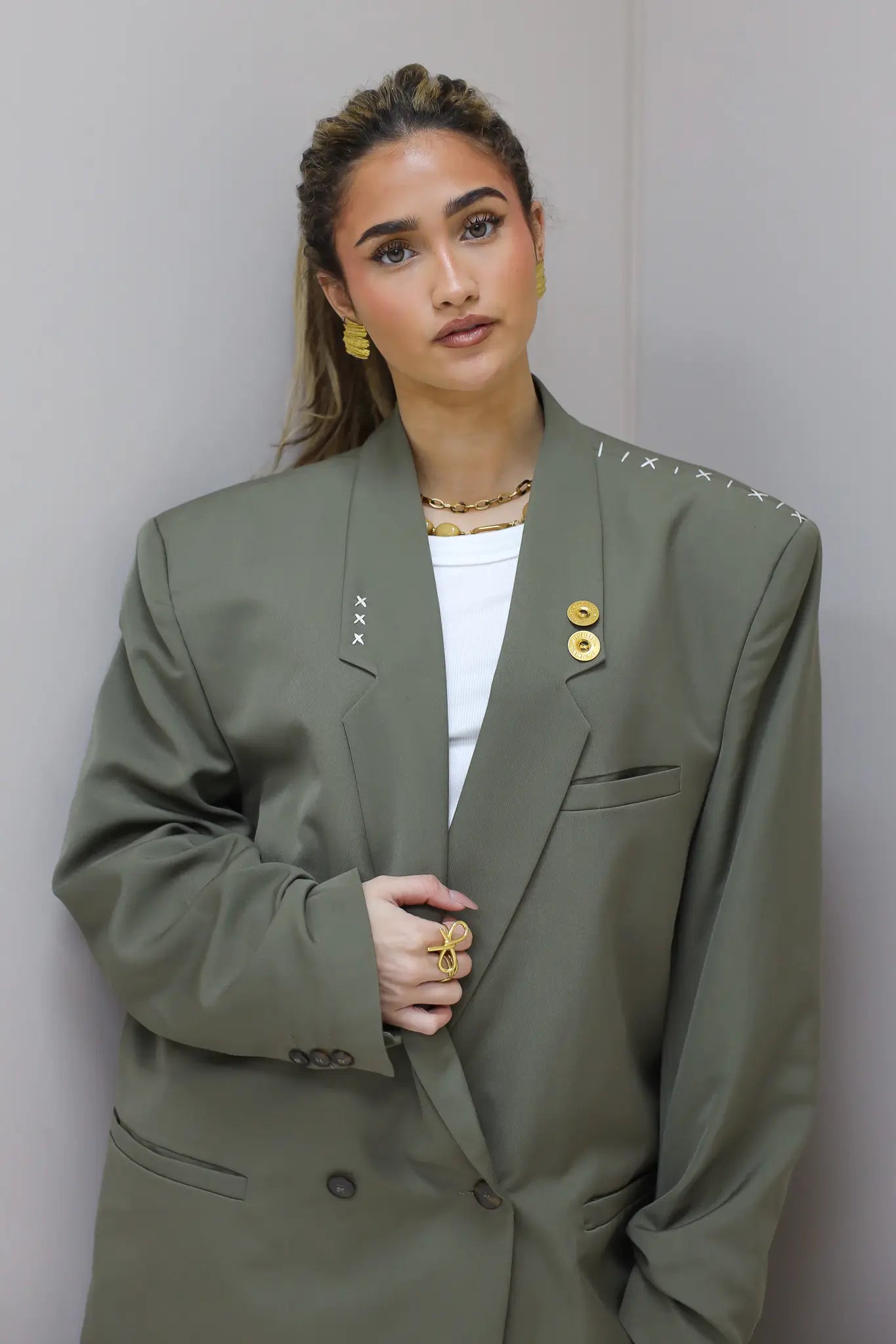 Close up van groene blazer met revers en goudkleurige pin