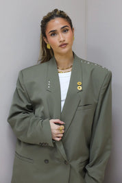 Close up van groene blazer met revers en goudkleurige pin