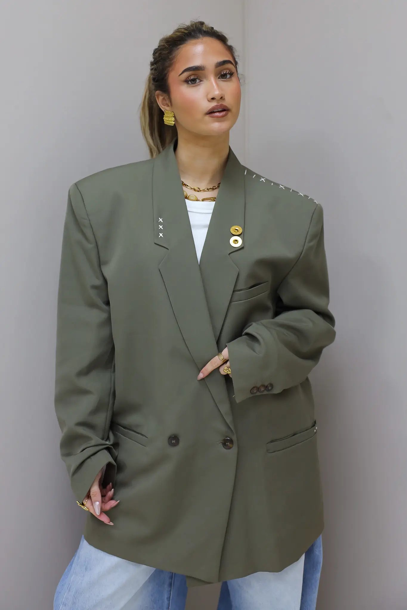 Detail van voorkant met dubbele knoopsluiting van groene blazer