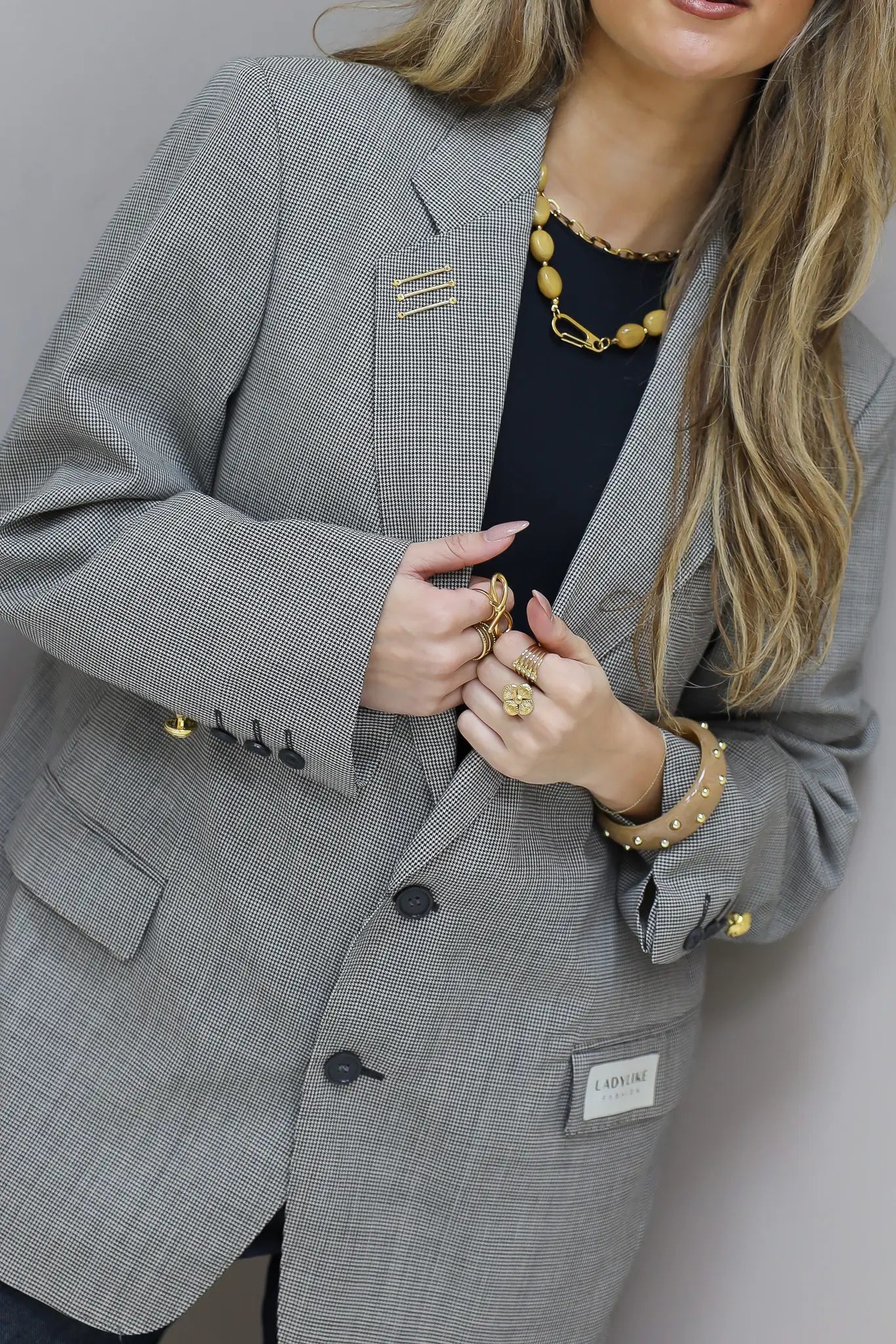 Detail van licht grijze blazer met knoopsluiting