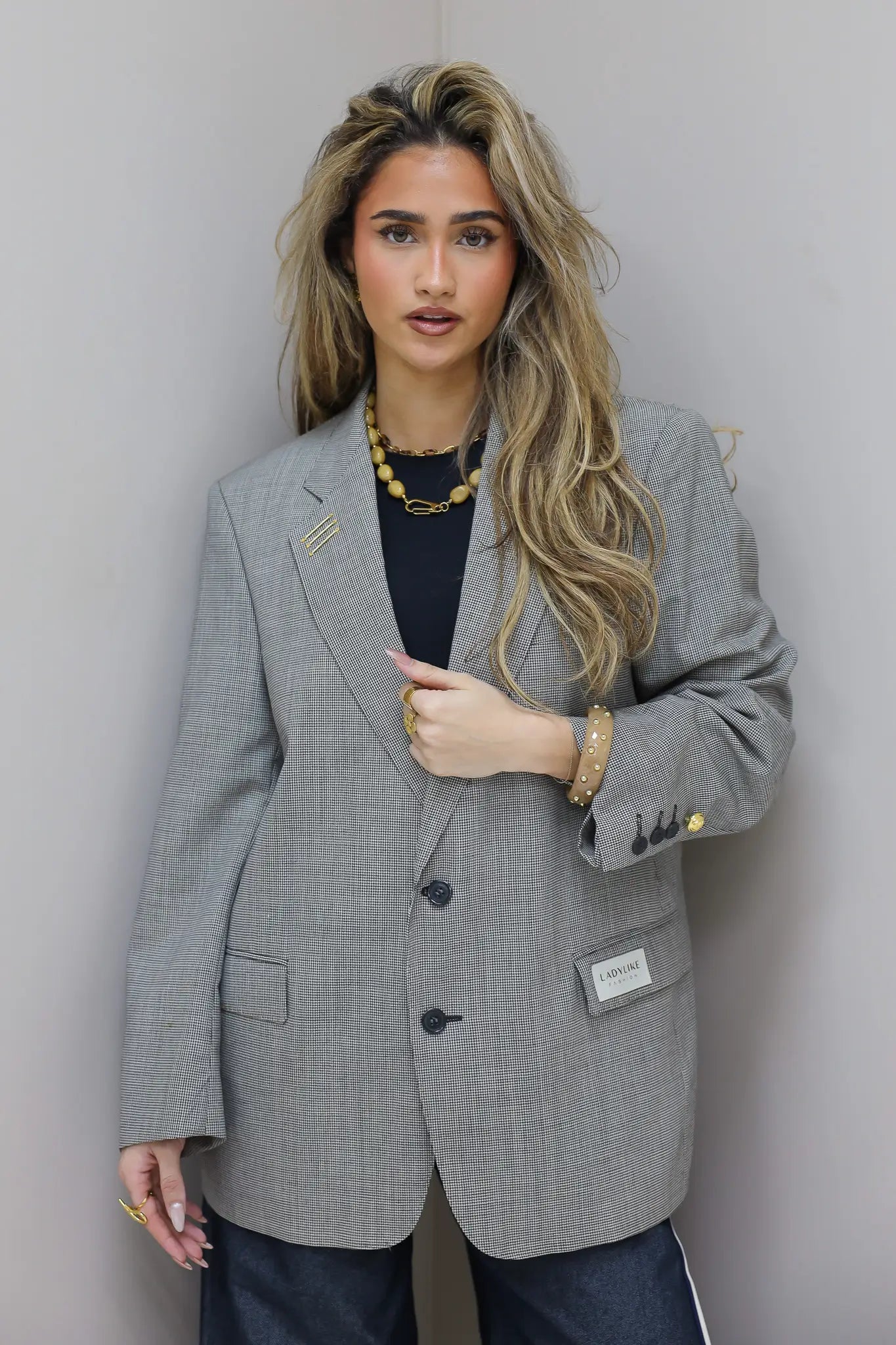 Oversized licht grijze blazer dames rechtstaand tegen muur