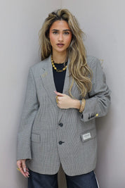 Oversized licht grijze blazer dames rechtstaand tegen muur