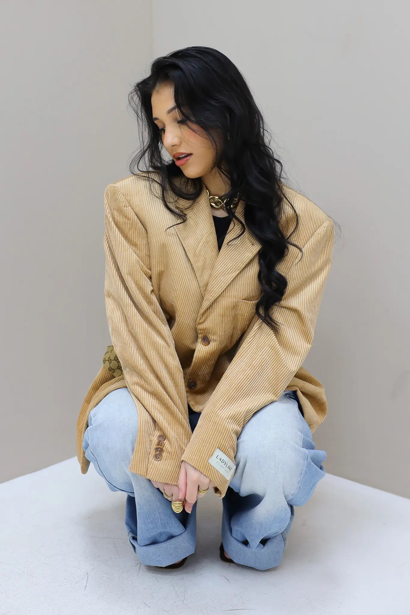 model zittend met camel blazer atelier series