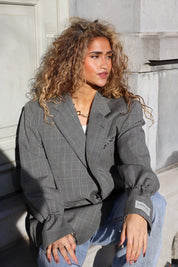 grijze ruit blazer dames staand bij gevel