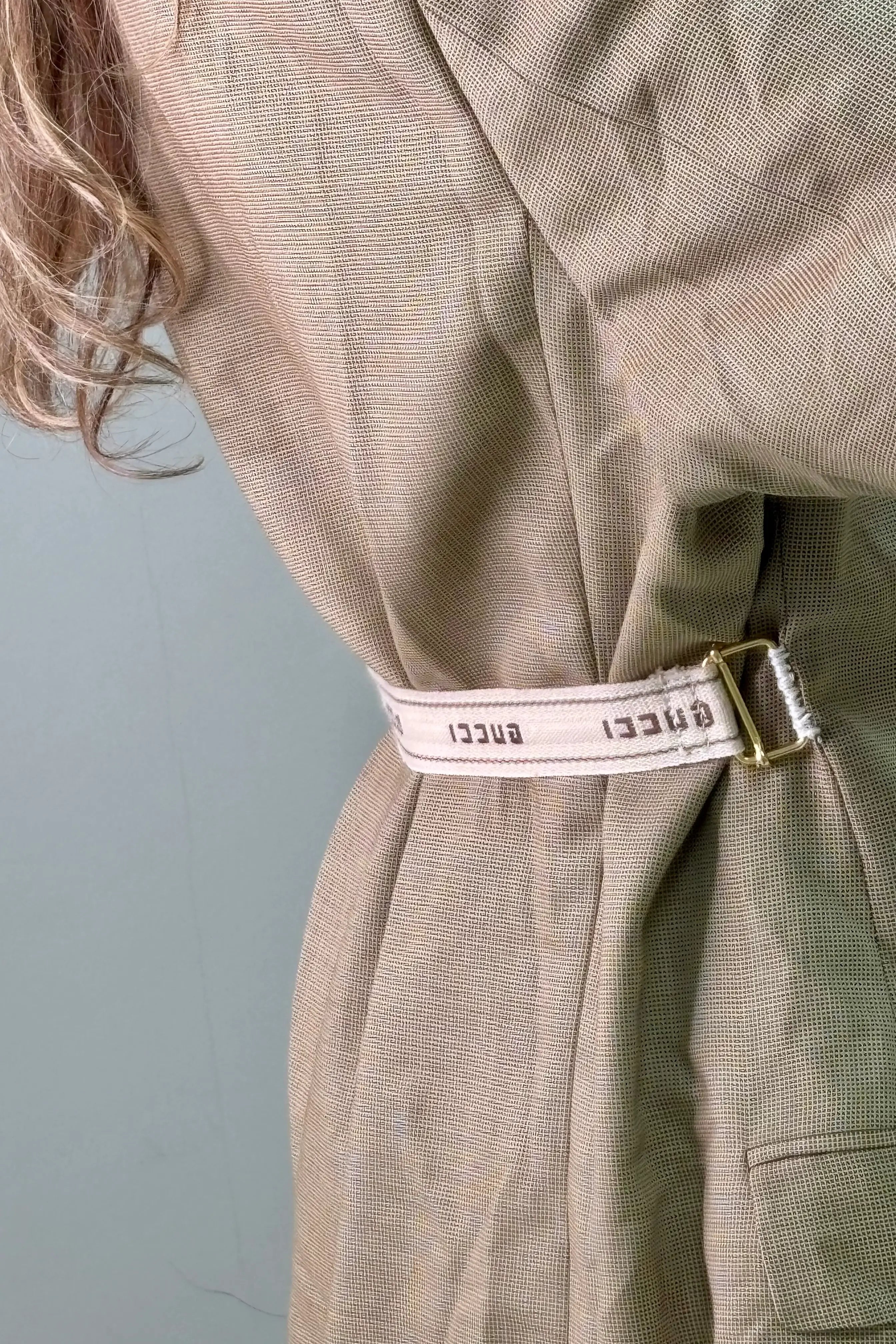 Detail van beige tailleband op de achterkant van de camel blazer