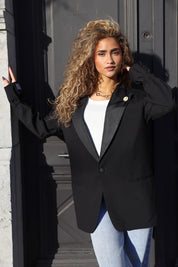 zwarte blazer dames staand bij donkere achtergrond