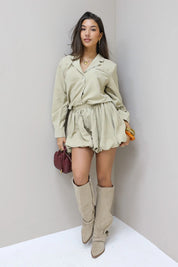 Model poseert tegen lichte muur in beige ballon skort