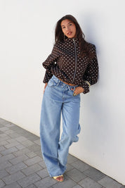 Model draagt barrel jeans omslag band blauw met zwarte top