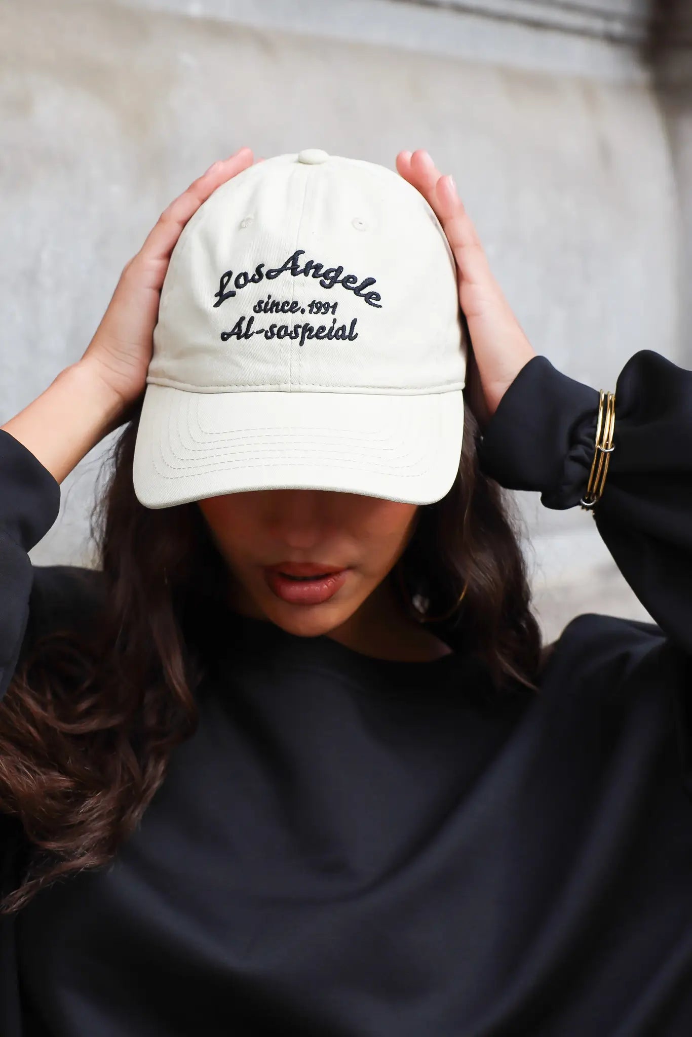 Beige dames pet met zwarte geborduurde tekst aan de voorkant gecombineerd met een zwarte sweater