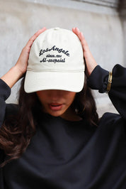 Beige dames pet met zwarte geborduurde tekst aan de voorkant gecombineerd met een zwarte sweater