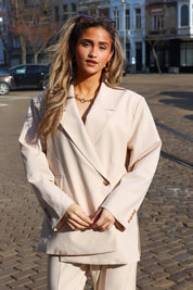 model draagt beige blazer dames pose ladylike