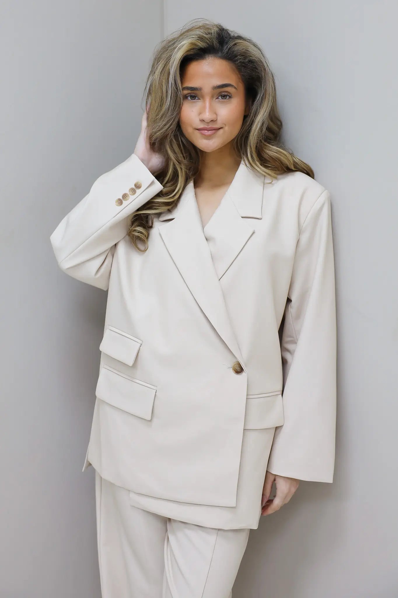 model draagt beige blazer dames studio pose ladylike