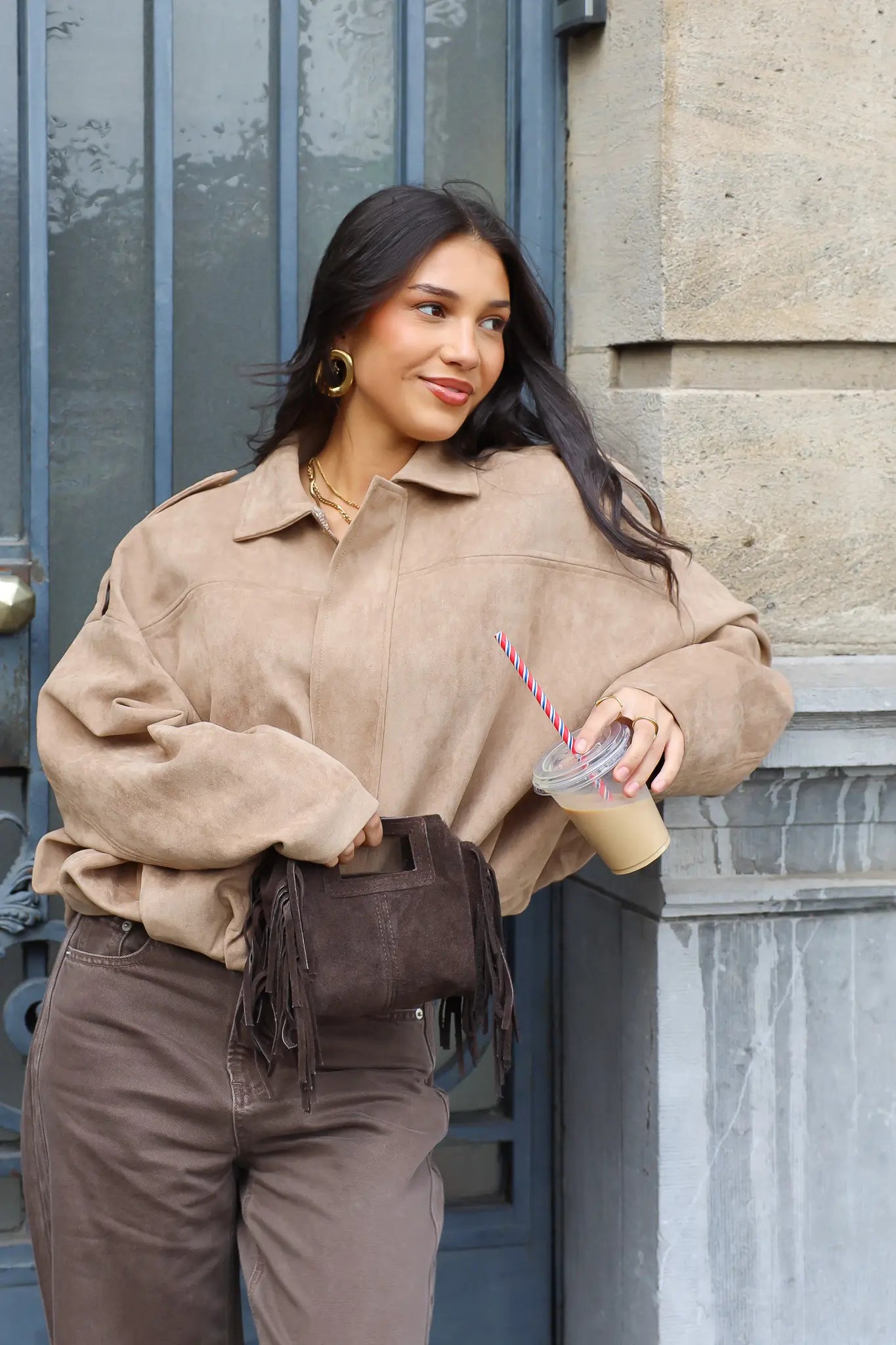 Model draagt een beige suede blouse buiten tegen een muur