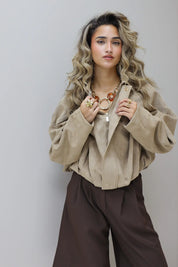 Studiofoto van model met beige suede blouse en bruine broek