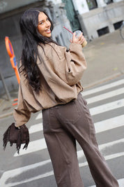 Model loopt op straat met een beige suede blouse