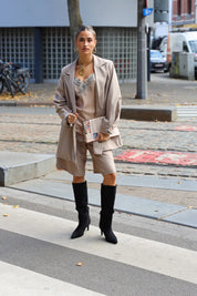 model loopt buiten in beige outfit met kanten top en laarzen