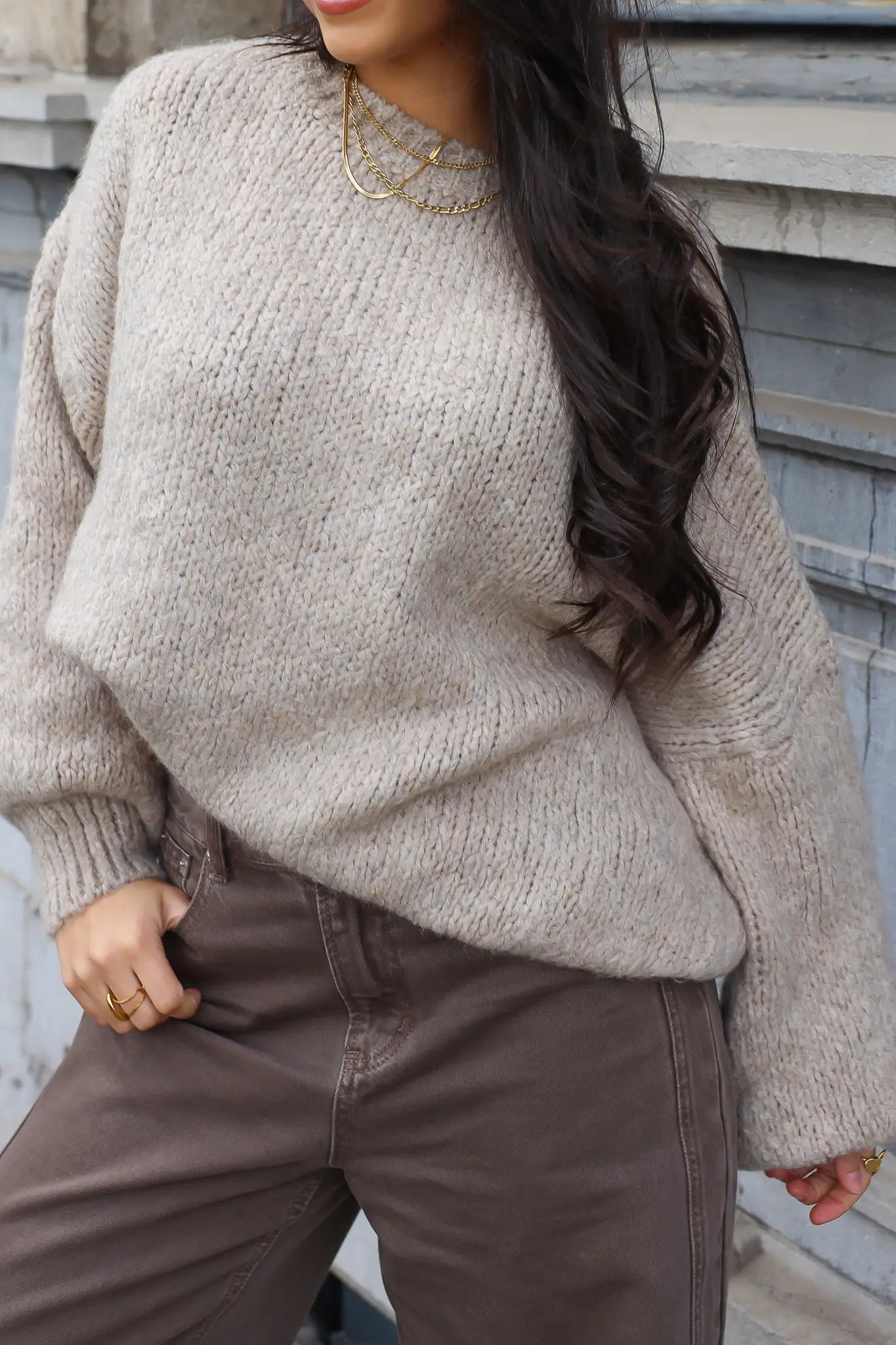 Close-up van beige trui met bruine broek en lange donkere haren