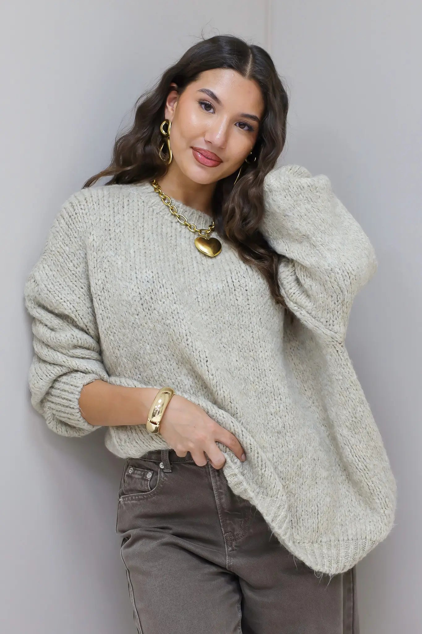 Model staat recht in beige trui met bruine broek