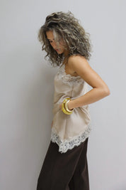 model met beige trui in nonchalante pose tegen lichte muur