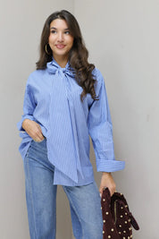 blauwe gestreepte blouse model recht van voren met tas naast het been