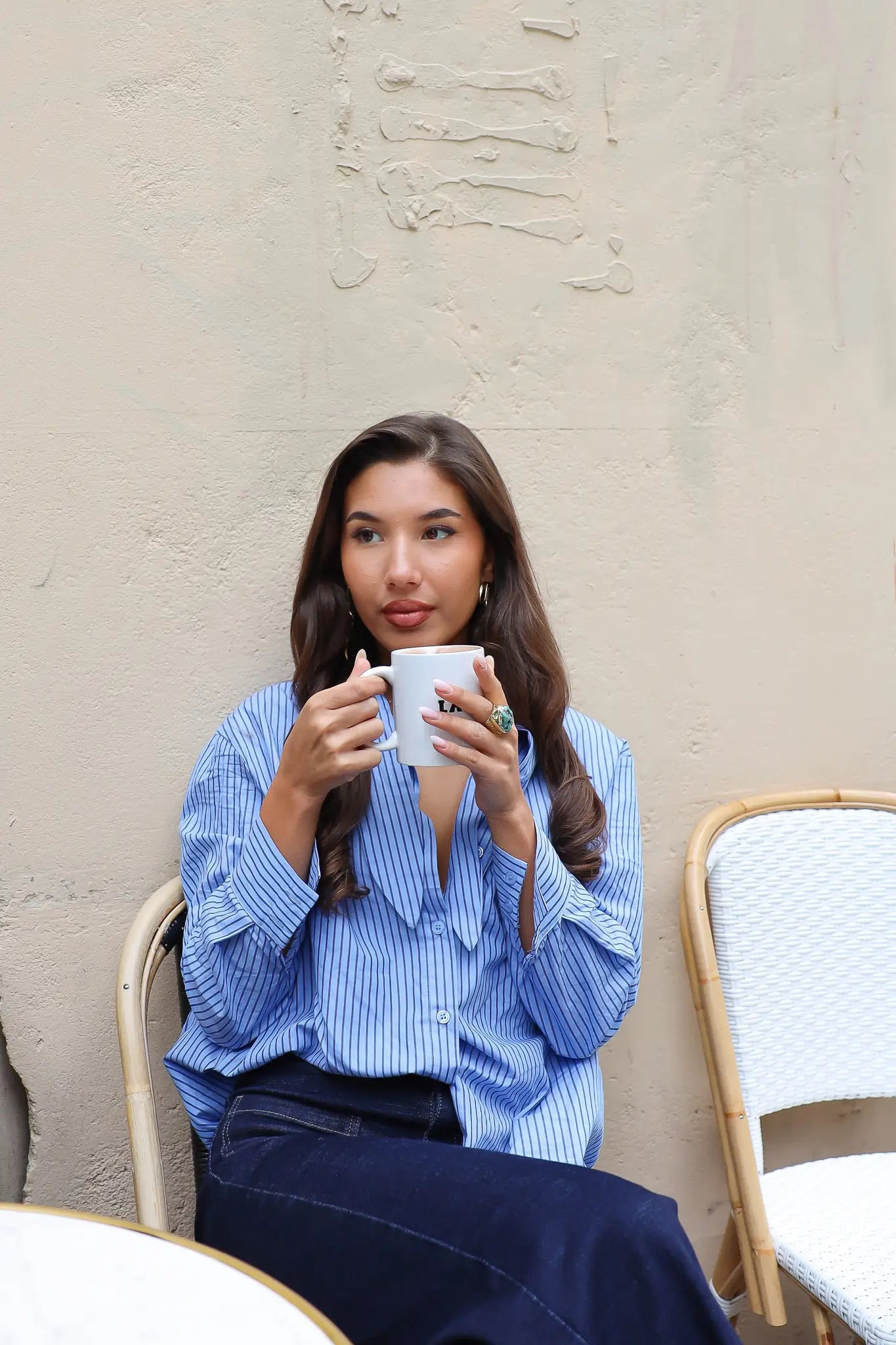 blauwe gestreepte blouse model zittend ontspannen met kop koffie