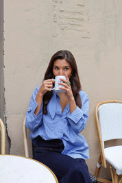 blauwe gestreepte blouse model zittend licht gedraaid met koffie