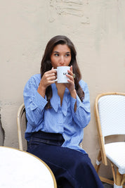 blauwe gestreepte blouse model zittend vooraanzicht met koffiekop