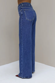 Blauwe wijde jeans vanaf de zijkant met lichte wassing