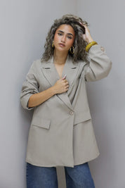 vrouw kijkt recht vooruit met beige oversized blazer en jeans