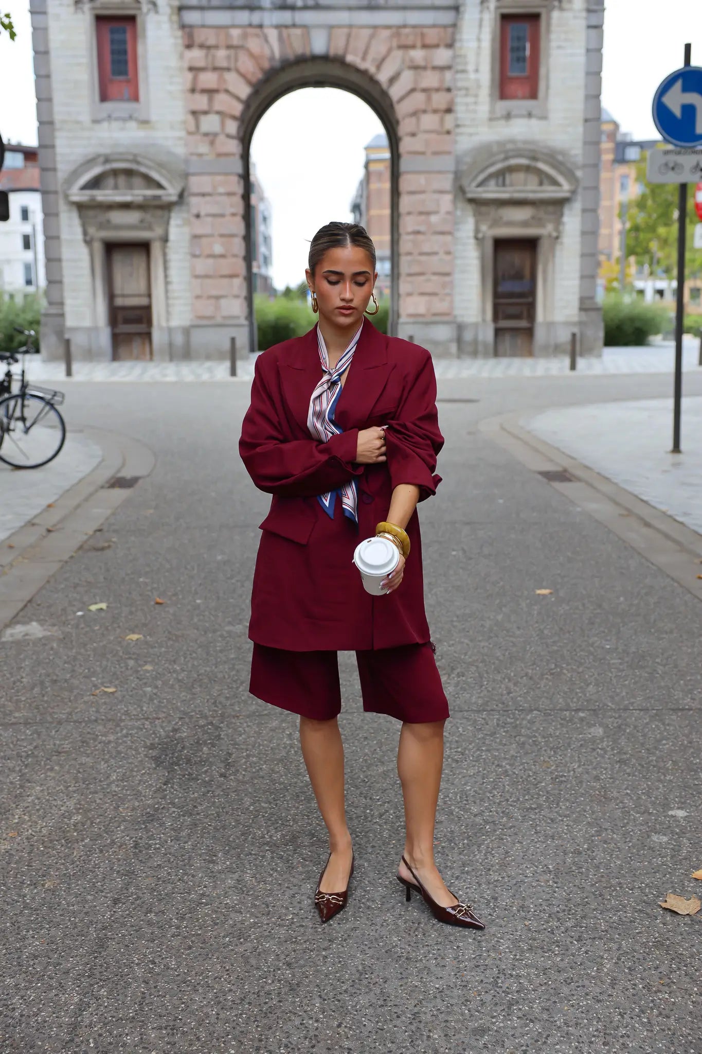 vrouw met bordeaux oversized blazer en hakken gefotografeerd buiten bij stadspoort
