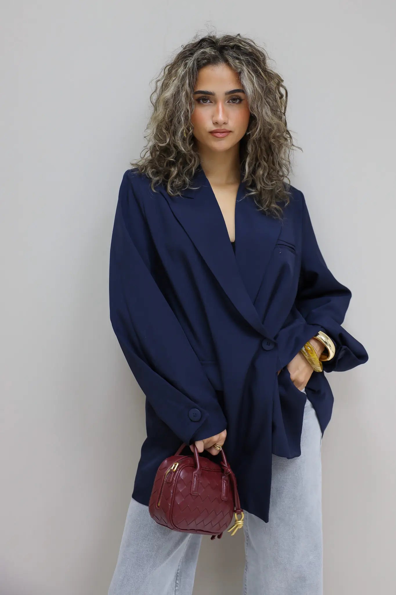 zijaanzicht van vrouw met donkerblauwe oversized blazer open gedragen op stoel