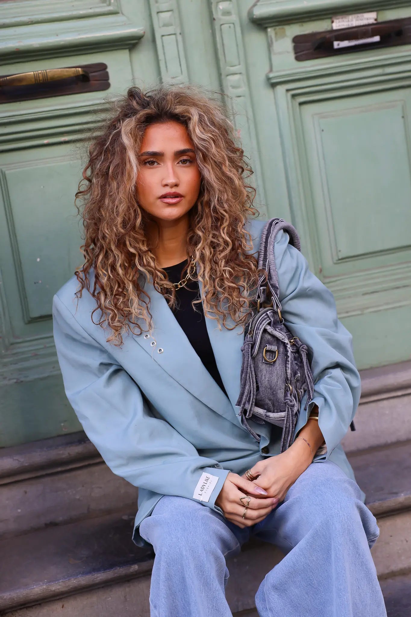 model zit op trap met mint groene blazer en jeans