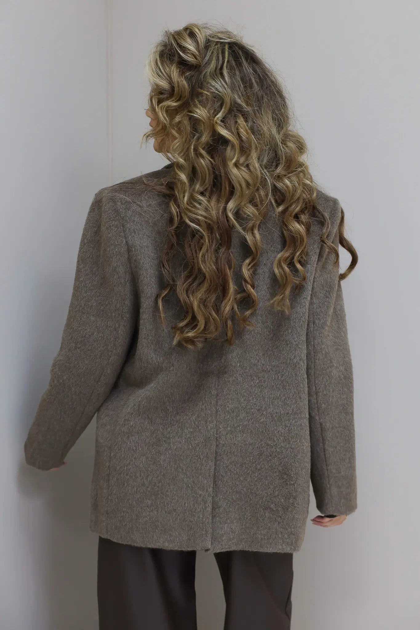 Achterkant van de taupe blazer, focus op pasvorm en wolstructuur