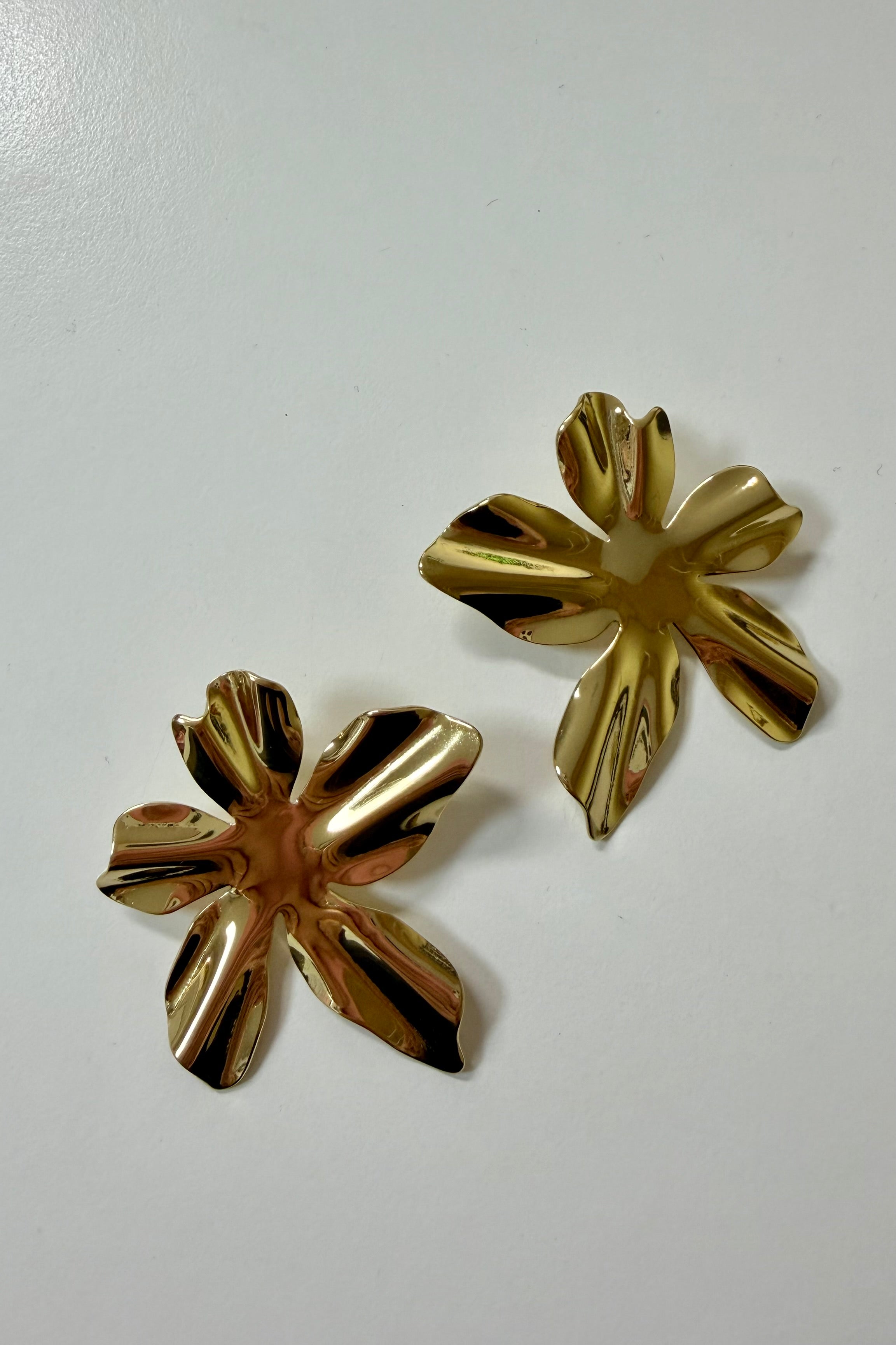 Grote bloem oorbellen goud op lichte achtergrond