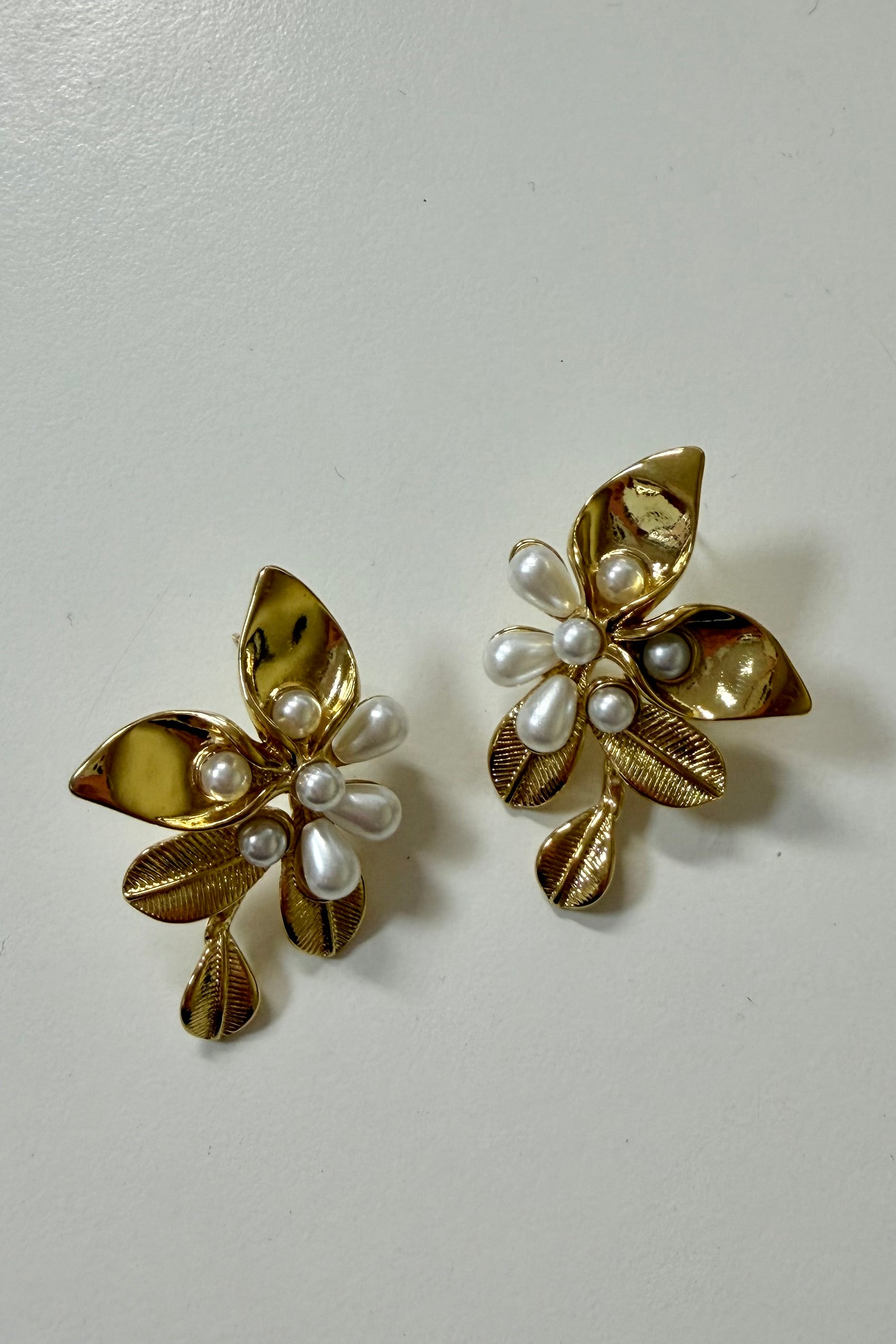 Bloem oorbellen goud met parels op lichte achtergrond